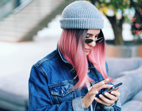 Young woman with pink hair using her smartphone