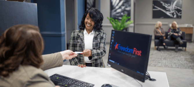 Smiling woman handing over a check to a Freedom First banker