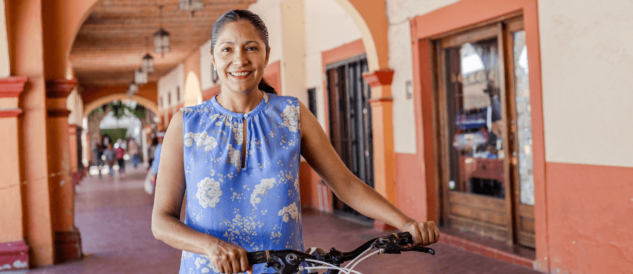 Smiling older woman with a bicycle in Latin America