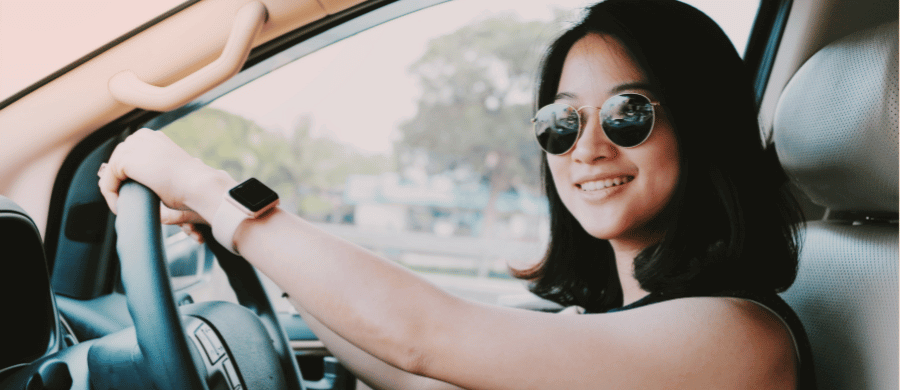 Young woman in sunglasses driving a car