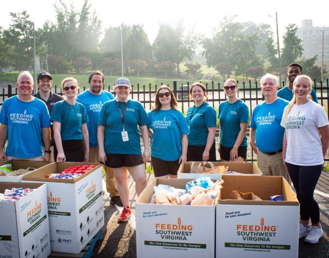 Group of people standing around boxes of food donations through Freedom First's Freedom to Give Drive with Feeding Southwest VA.