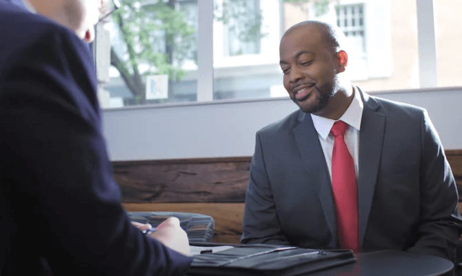 Smiling man in a suit speaking with a Freedom First banker