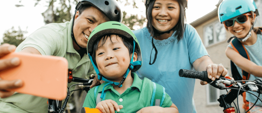 Smiling family of 4 taking a selfie with bicycles