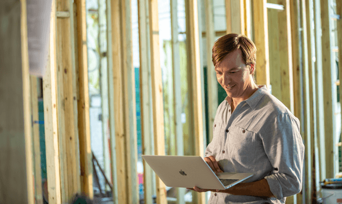 Entrepreneur Brent Cochran looking at laptop while on construction site