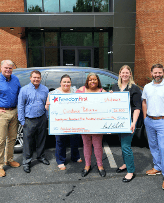 Picture of Constance with Freedom First staff holding a check for her auto loan payoff