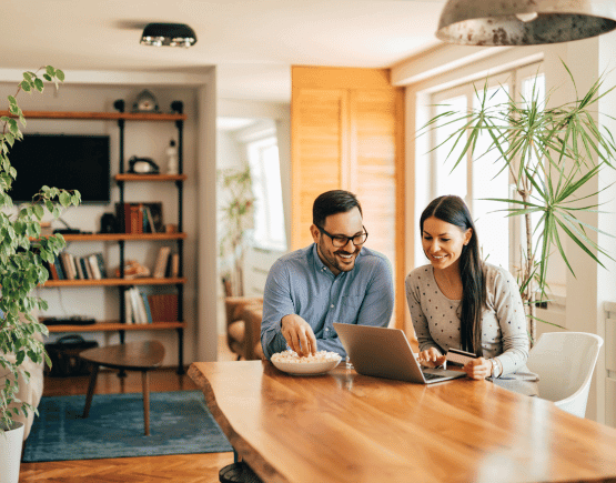 Young couple using a credit card and laptop at home