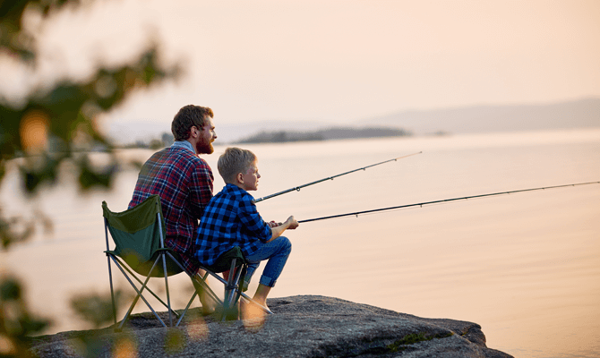 Young father and son fishing on a river