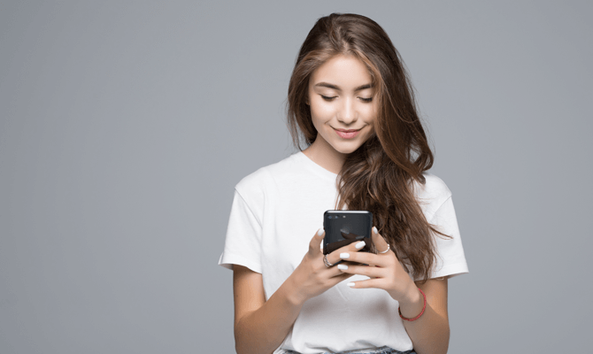 Young woman looking down at smartphone in hand and smiling