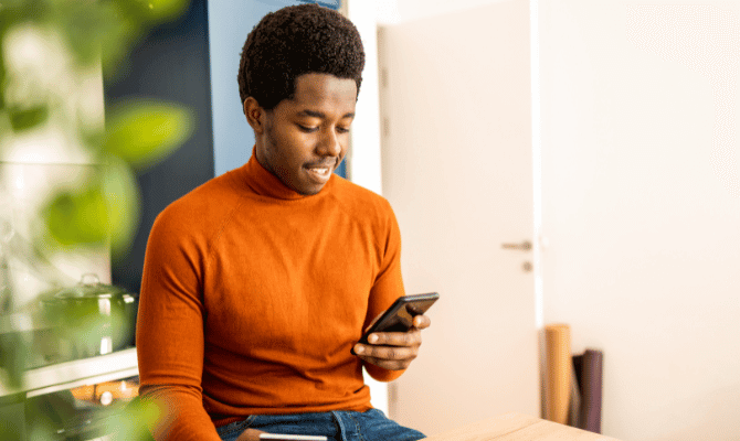 Young man smiling down at his smartphone