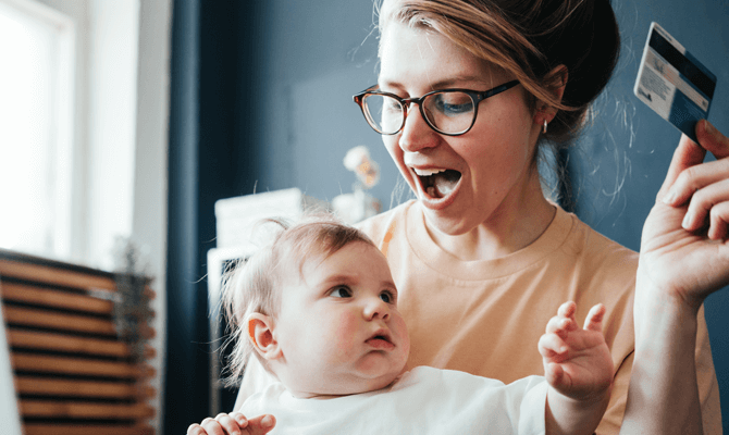 Mother holding credit card out of reach of baby