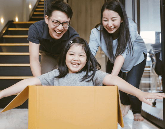 Young parents playing with their daughter in a cardboard box on moving day
