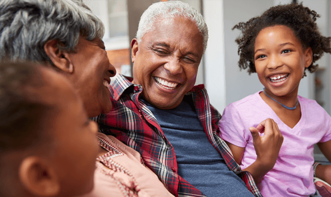 A pair of grandparents laughing with their two grandchildren