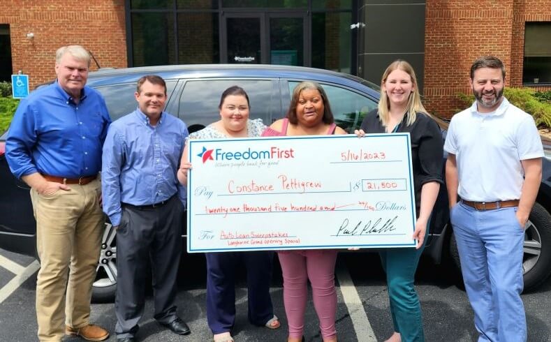 Freedom First employees presenting auto loan payoff check to winning member