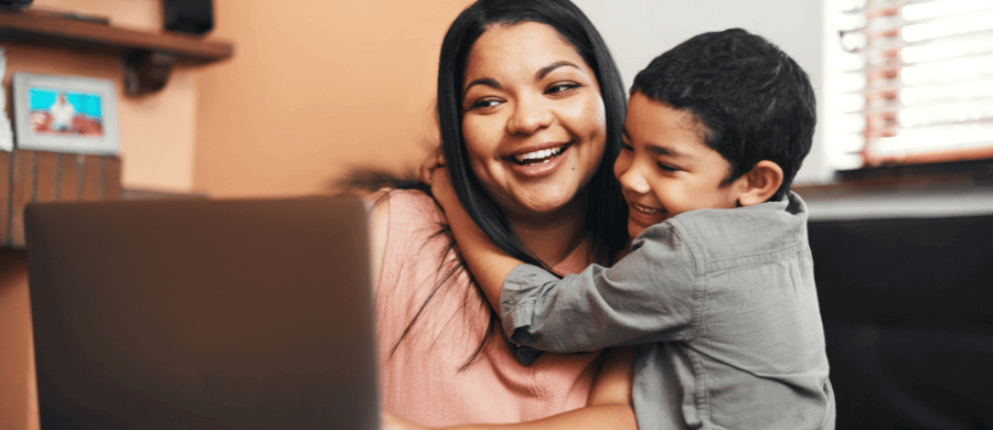 Young mother hugging son while using laptop