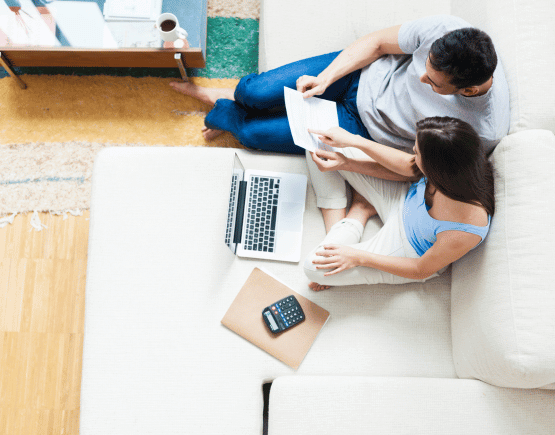 Aerial view of young couple reviewing finances with a laptop and calculator