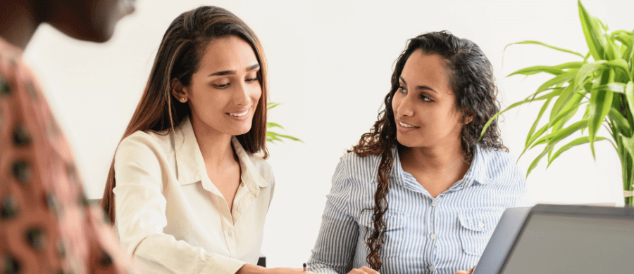 2 young professional women talking to each other at work