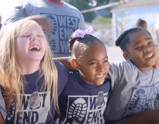 Three smiling children hugging at the West End Center for Youth