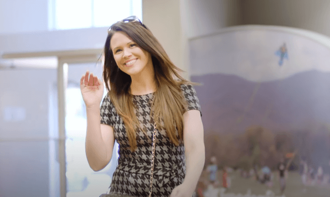 Young woman smiling and waving while walking into Freedom First branch