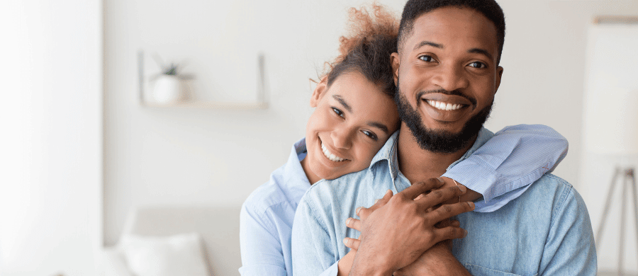 Smiling young woman hugging man from behind