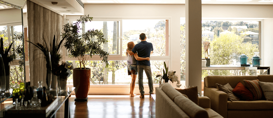 Couple standing in luxurious living room looking out window