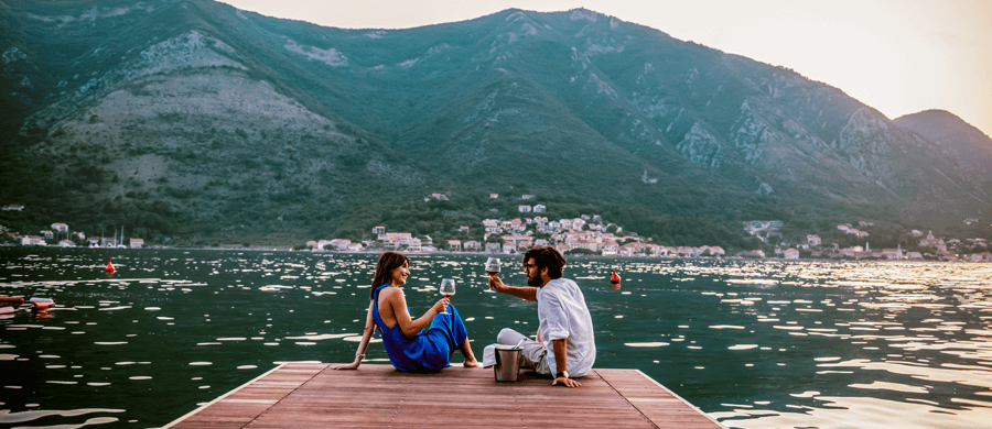 Couple toasting wine on a dock at a mountain lake