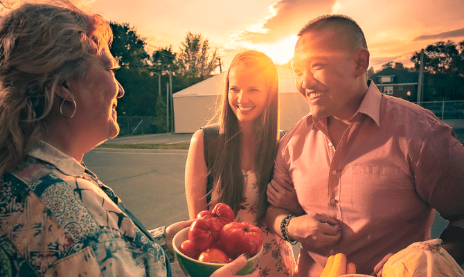 Smiling couple speaking to a vendor at the Roanoke West End farmer's market