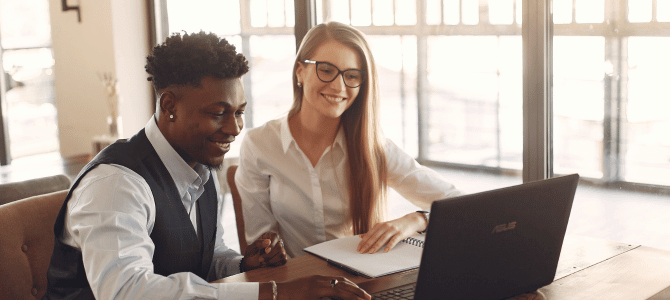 Two colleagues looking at a laptop together