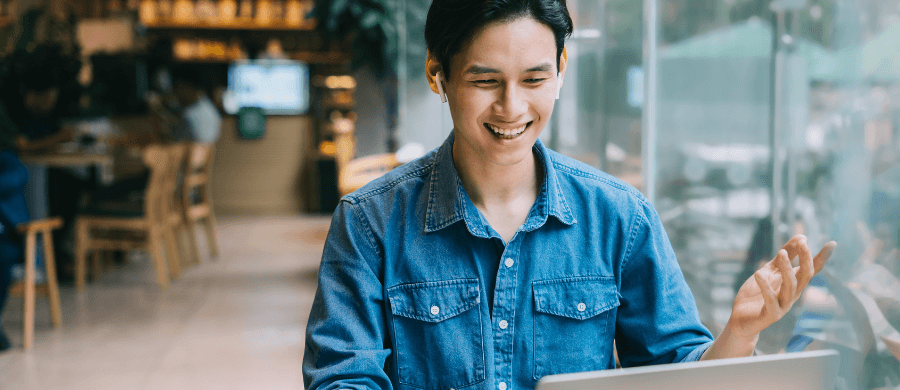 Smiling young man using laptop in a cafe