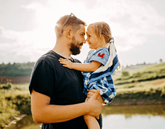 Young father holding toddler daughter outside