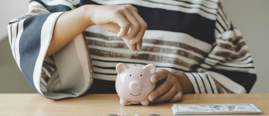 Hands placing coins in a piggy bank