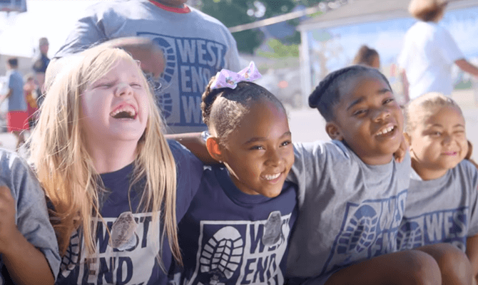 Four smiling children hugging at the West End Center for Youth