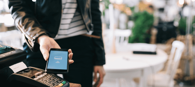 Person using their smartphone's mobile wallet feature to pay at a cafe