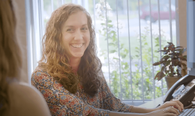 Smiling woman at Freedom First branch typing