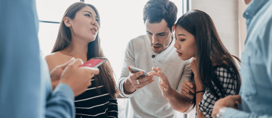 Young man showing 2 women something on his smartphone