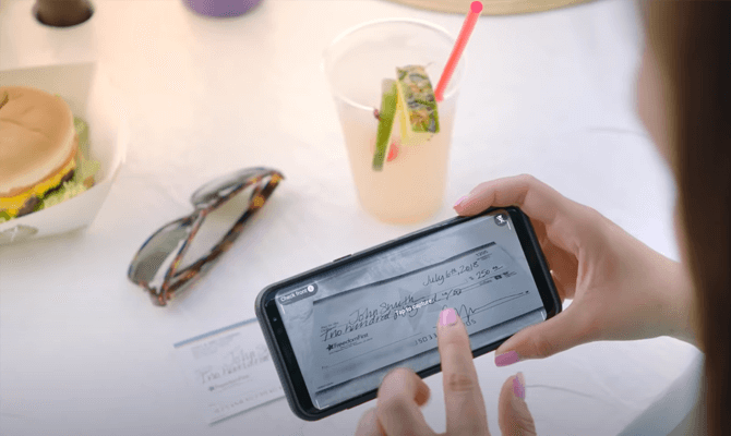 Woman depositing check with mobile phone over lunch