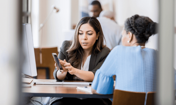 Banker showing client something on her smartphone