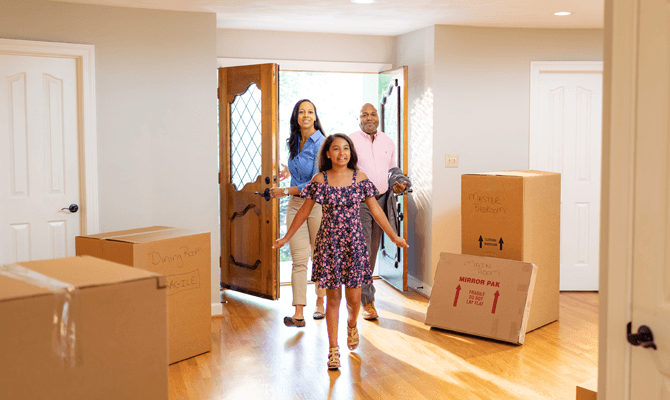 Family of three walking into their new home on moving day