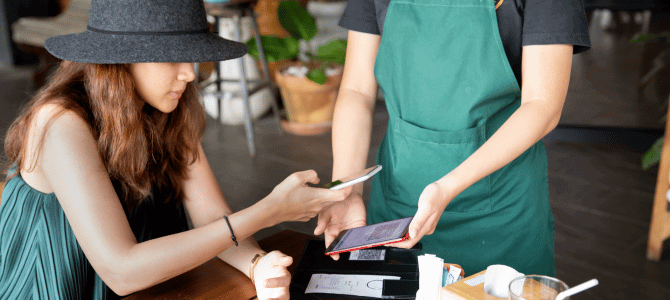 Woman paying for coffee with a QR code using her smartphone